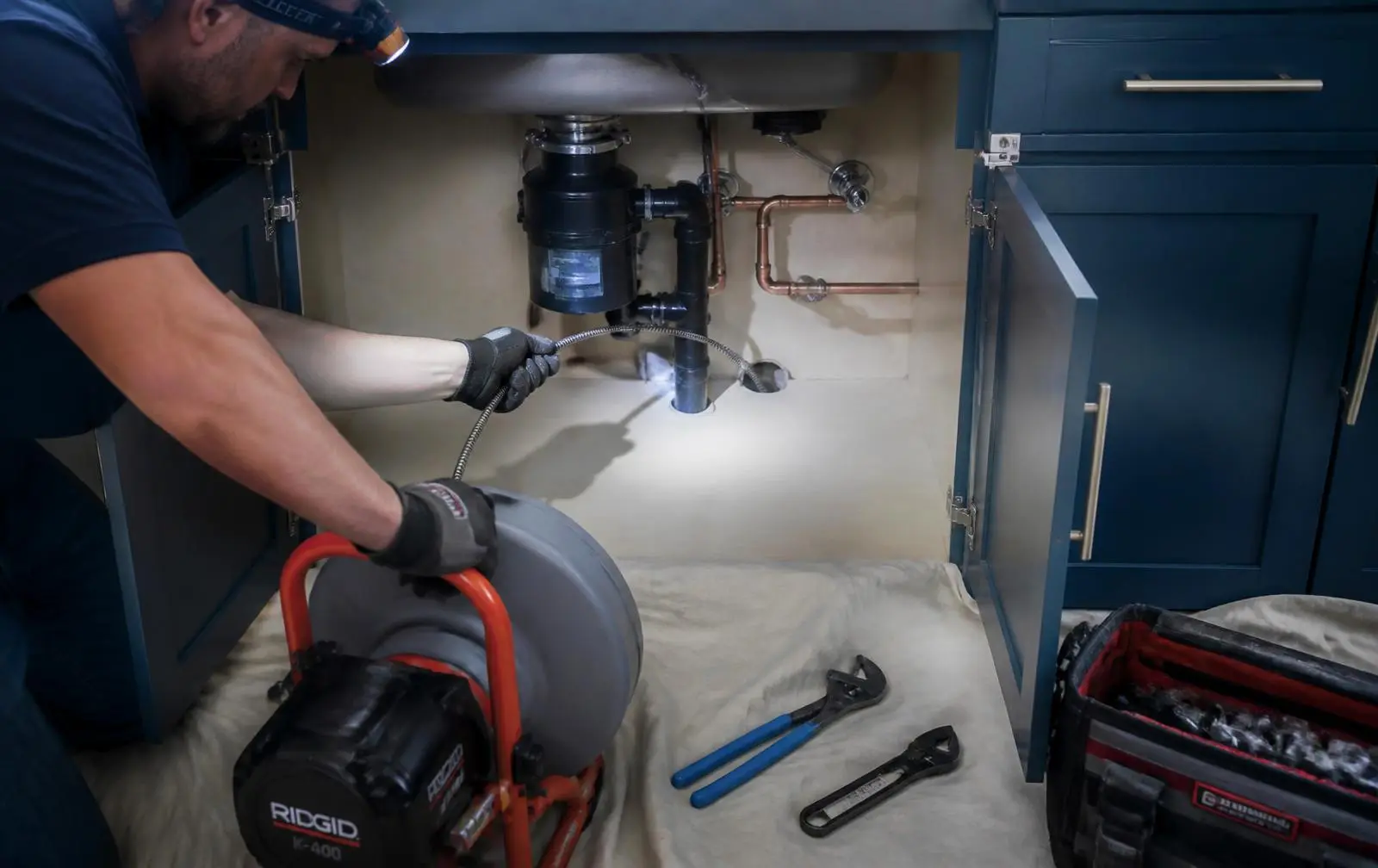 Plumber feeding a sewer inspection camera into a cleanout while the monitor shows the inside of a clay pipe
