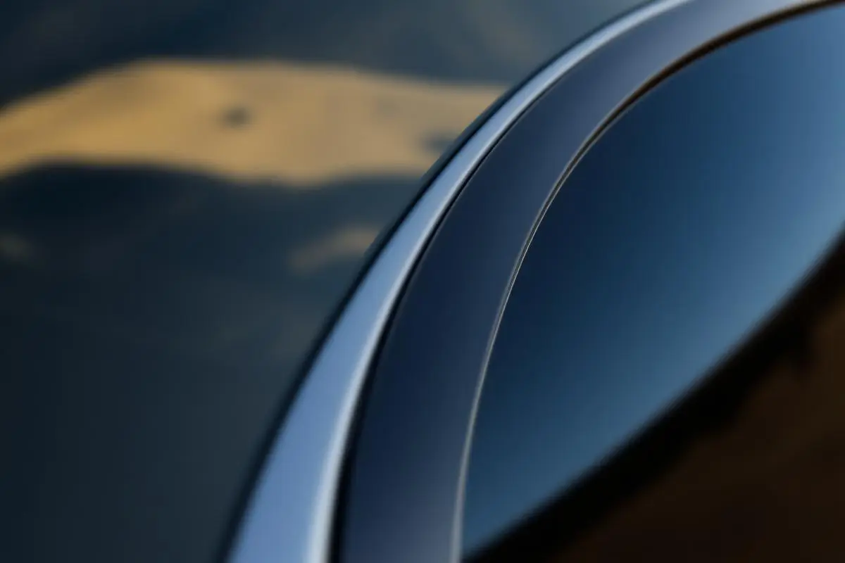 A close-up of a tinted car window showing a clean film edge and a reflection of golden hills